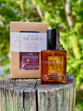 Perfume bottle labeled 'The Stockman' by 'Made at The Ranch' on a wooden surface with a natural background.